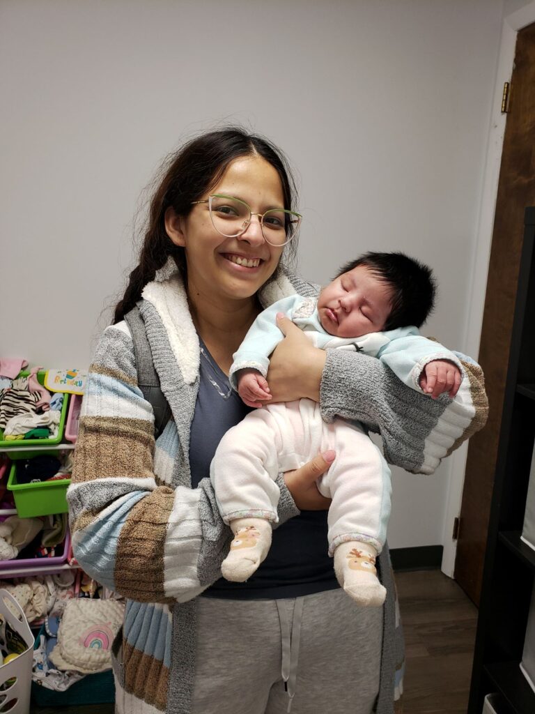 A smiling mother holds her sleeping baby at Bright Hope Pregnancy Support Centers.