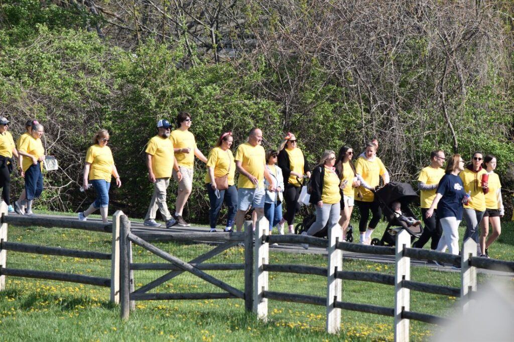 A group of people, most wearing yellow event T-shirts, walk on the path outside the Charles Chrin Community Center during the 2026 Lehigh Valley Walk for Life held by Bright Hope Centers in Easton, Pennsylvania.